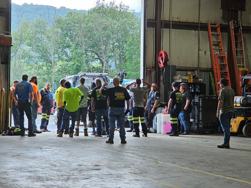 Operators gather around instructor near shop bay