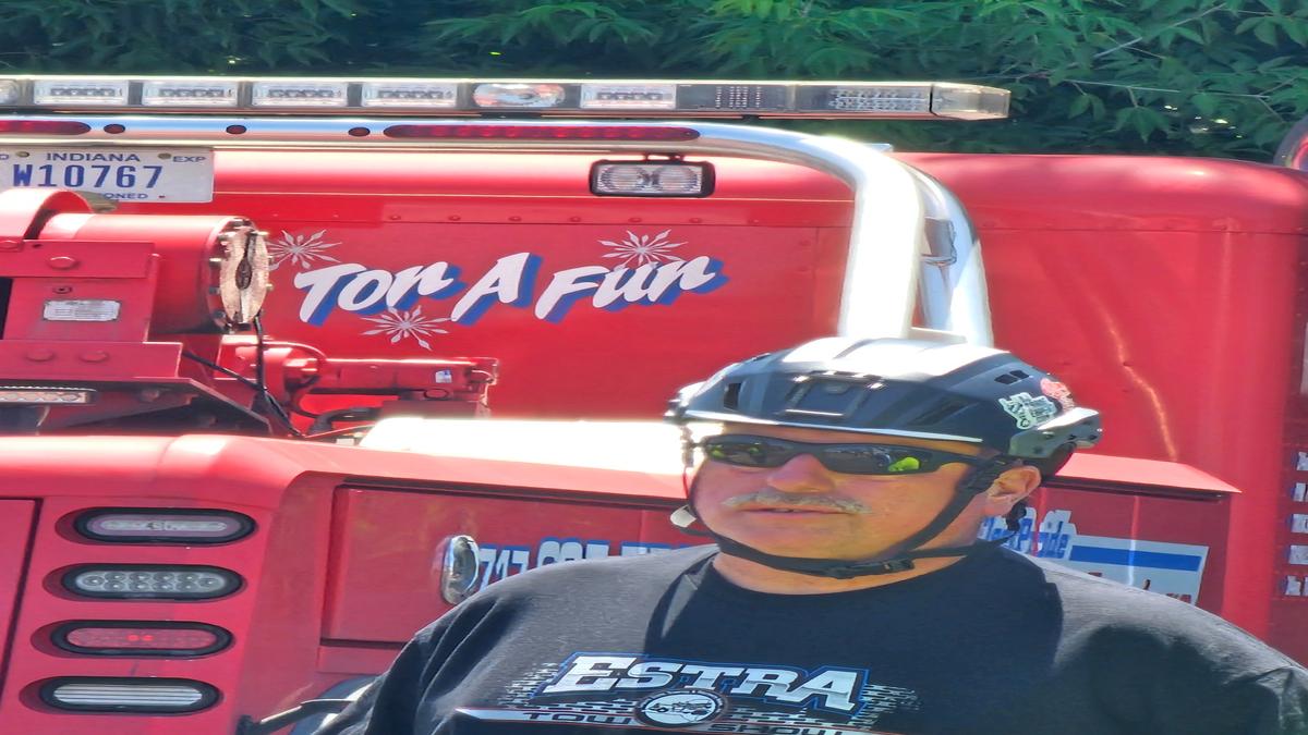 Trainer in safety helmet standing in front of red tow truck during Scomac towing safety training
